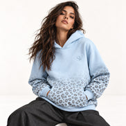 Model sitzt im hellblauen Leopard Print Hoodie von Santana Vega