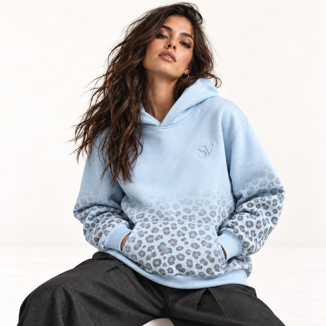 Model sitzt im hellblauen Leopard Print Hoodie von Santana Vega